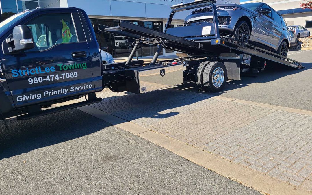 StrictLee Towing flatbed loading an SUV at a dealership